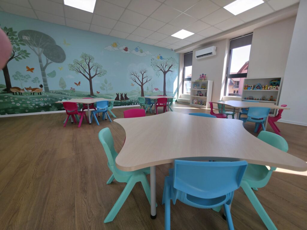 Sala de grupă Licurici — perete pictat cu pădure